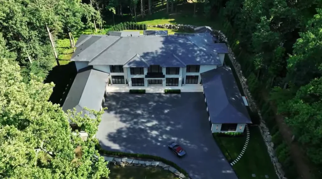 Aerial view of a modern house with a spacious driveway surrounded by greenery.